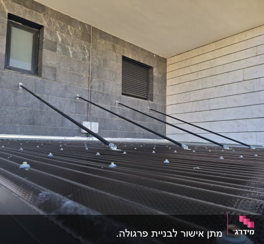 גג מתכת עם ברגים ותמיכות מתכת לקיר